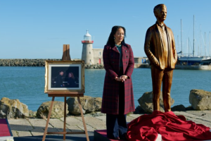 Tamera Mowry-Housley as Gethsemane standing near a memorial on a dock in Haunted Harmony Mysteries: Buried at C